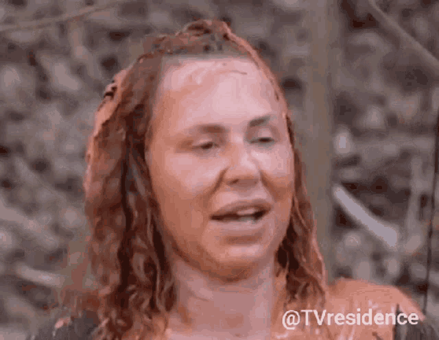 a woman with her face covered in mud is smiling .