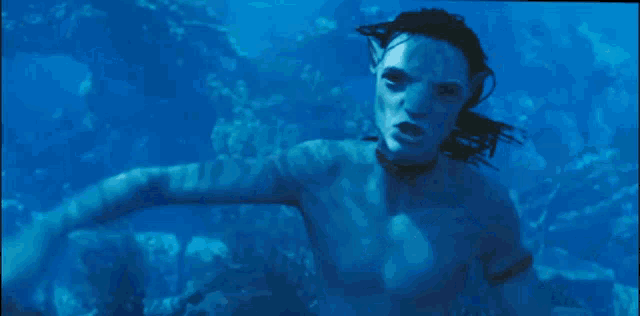 a man with dreadlocks is swimming in the ocean .