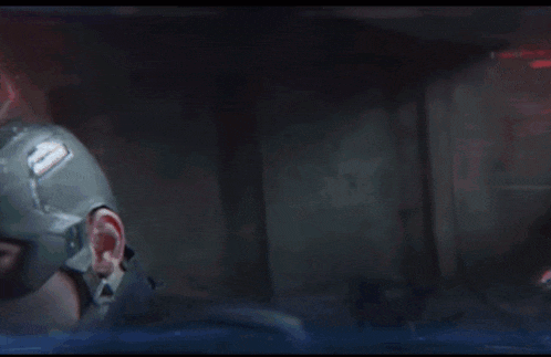 captain america is holding a shield in his hand in a dark room .