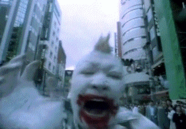 a person with white paint on their face is screaming in a crowded street