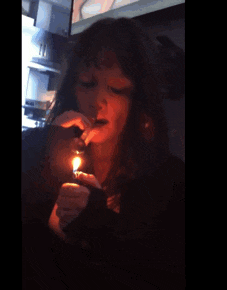 a woman is smoking a cigarette with a lighter