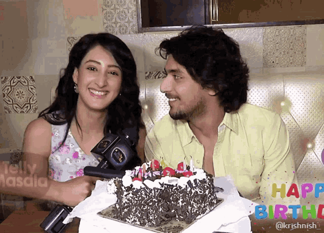 a man and a woman sitting in front of a cake that says happy birthd