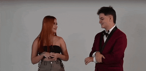 a man in a tuxedo and a woman in a strapless top are standing next to each other and smiling .