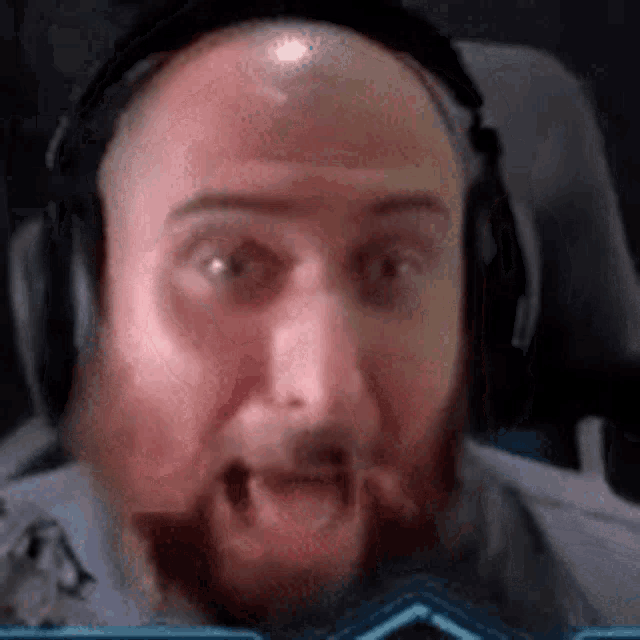 a bald man with a beard is wearing headphones while sitting in a chair .