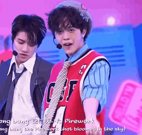 a man in a suit and tie is standing next to another man in a red jersey that says firework on it