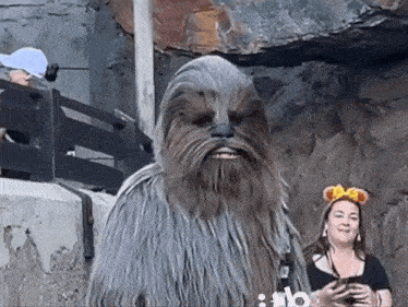 a chewbacca costume is being worn by a woman holding a cell phone