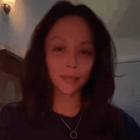 a woman wearing a black shirt and a necklace looks at the camera .