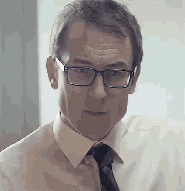 a man wearing glasses and a tie looks serious