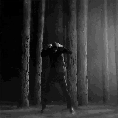 a black and white photo of a person dancing in a forest