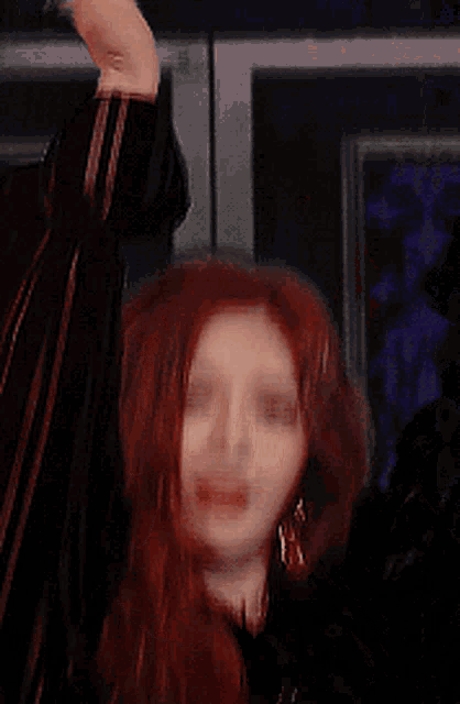 a close up of a woman 's face with red hair pointing at the camera