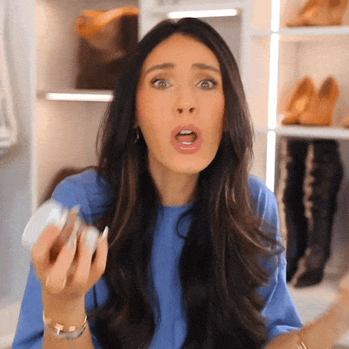 a woman with a surprised look on her face is holding something in her hand