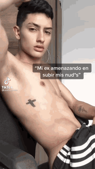 a shirtless young man with a cross tattoo on his chest