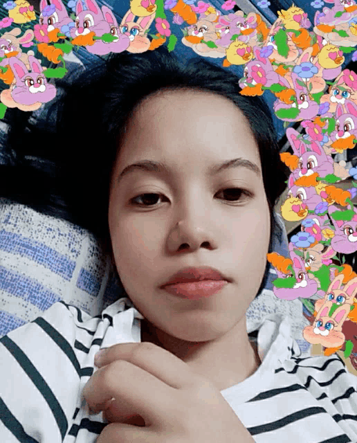 a girl is laying on a bed with a bunch of cartoon rabbits on her head