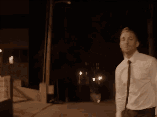 a man in a white shirt and black tie is standing in front of a sign that says this life is beautiful