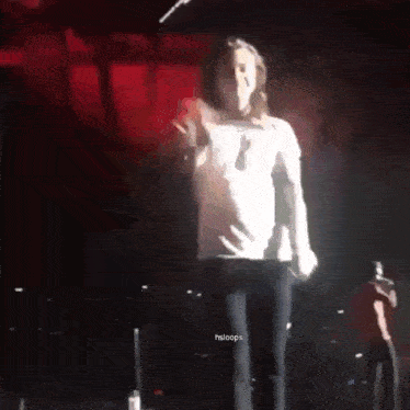 a man with long hair is standing on a stage with a microphone in his hand .