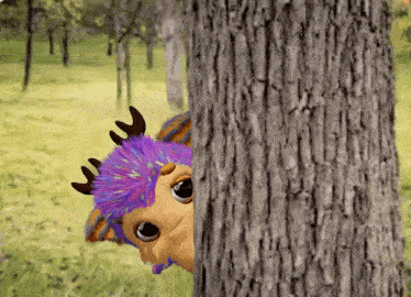 a stuffed animal with antlers peeking out from behind a tree trunk