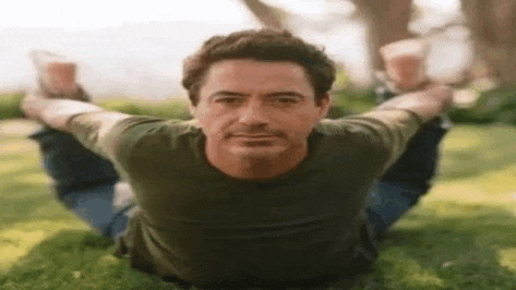 a man is laying on his back in the grass with his arms outstretched .
