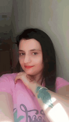 a woman in a pink shirt has a tattoo on her wrist