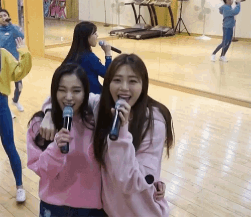 a group of girls singing into microphones in a gym