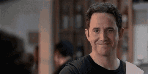 a man in a black shirt is smiling while standing in a room .