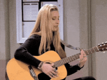 a woman is playing an acoustic guitar with a black sweater on