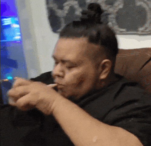 a man with a bun on his head is eating a sandwich