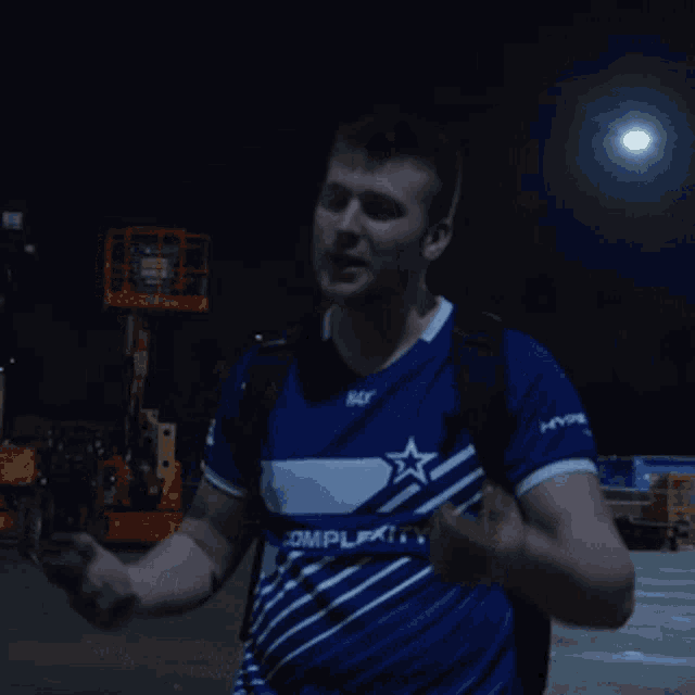 a man wearing a blue shirt with a white star on it is looking at his phone