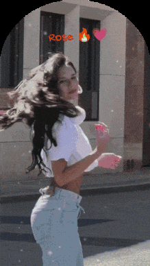 a woman in a white crop top is standing in front of a building with the word rose on it