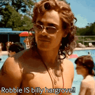 a shirtless man wearing sunglasses and a necklace is standing next to a pool .