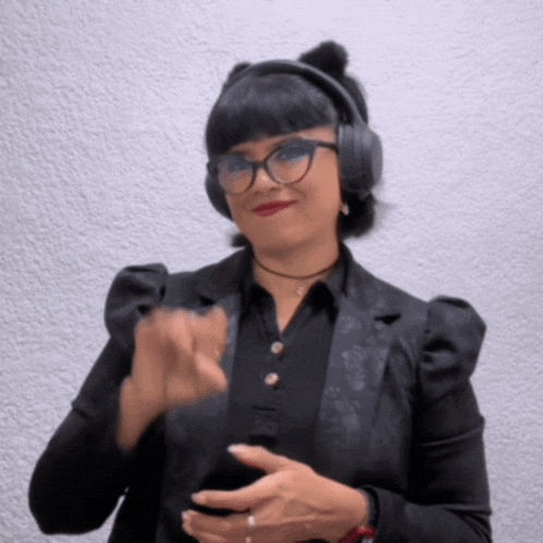a woman wearing headphones and a black jacket is clapping