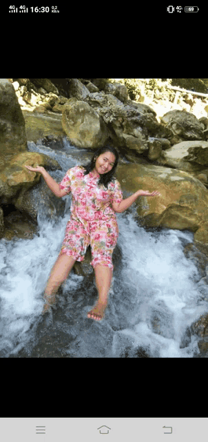 a woman in a pink floral dress is standing in a stream