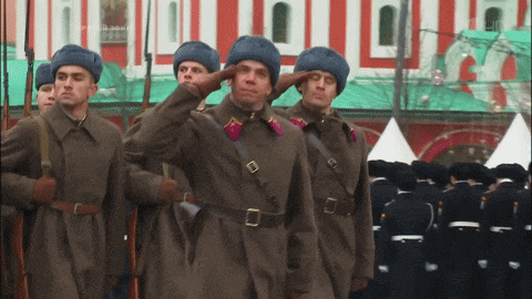 a group of men in military uniforms salute in front of a building that says ' russia 2004 ' on it