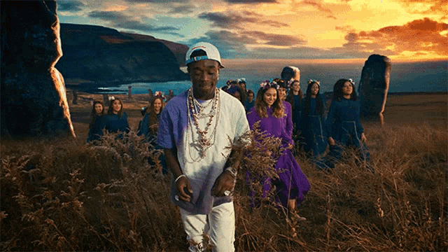 a group of people standing in a field including a man wearing a white hat