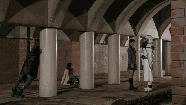 a group of people are standing in a tunnel with columns
