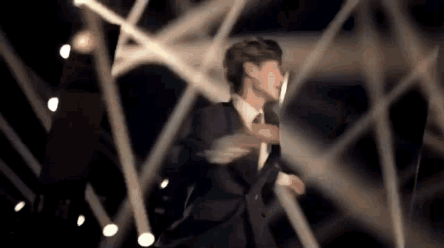 a man in a suit and tie is dancing in front of a crowd on a stage .