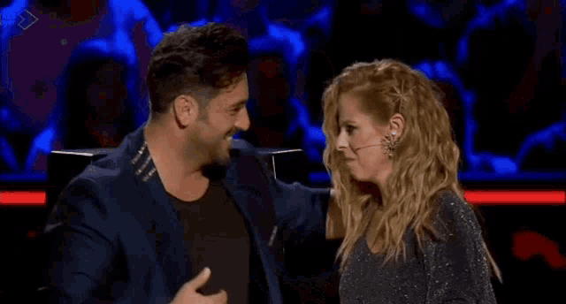 a man and woman are sitting next to each other on a stage .