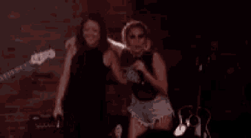 two women are standing next to each other in a dark room .