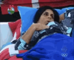 a woman is laying in a bed with a blue blanket that has the olympic symbol on it