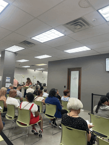 a group of people sitting in a waiting room with a sign on the wall that says ' a ' on it