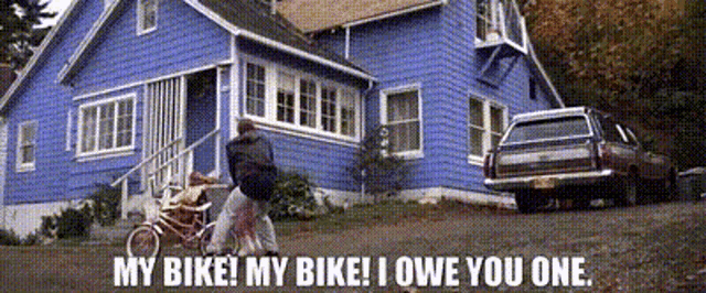 a man riding a bike in front of a blue house with the words my bike my bike i owe you one below him