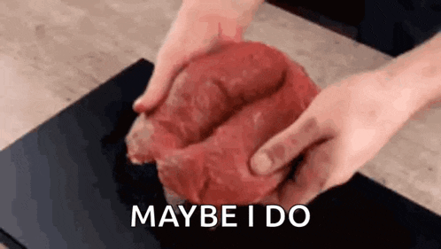 a person is holding a large piece of meat in their hands and saying `` maybe i do '' .