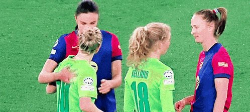 a group of women are standing on a soccer field hugging each other .