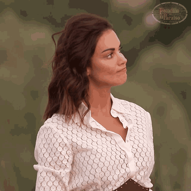 a woman in a white lace shirt stands in front of a sign that says paradise on it