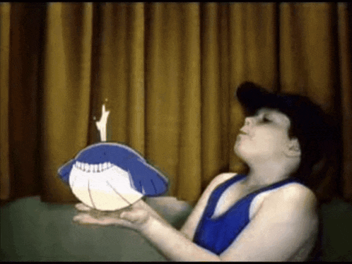 a boy blows out a candle on a whale shaped cake
