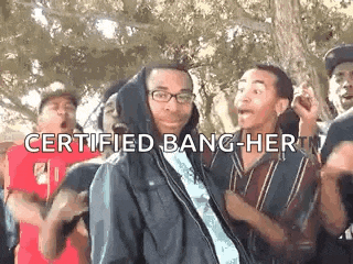 a group of young men are dancing in a park and one of them is wearing a hoodie and glasses .