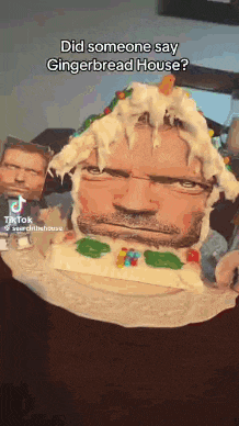 a man 's face is on top of a gingerbread house cake .