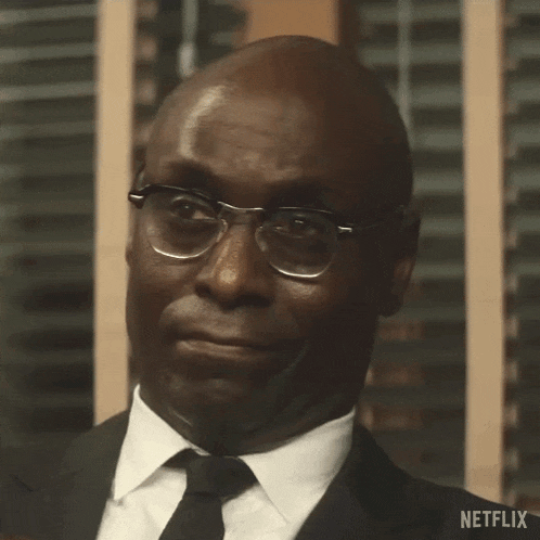 a man wearing glasses and a suit is smiling and looking at the camera .
