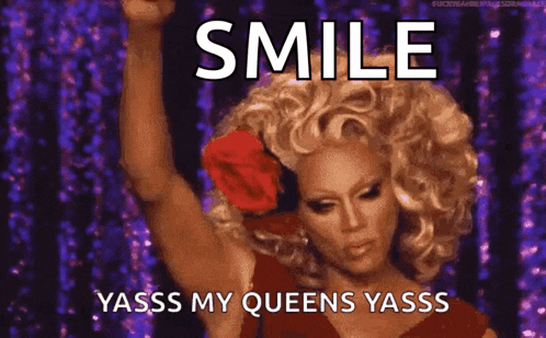 a drag queen with a rose in her hair is smiling and says smile yasss my queens yasss