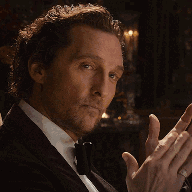 a man in a tuxedo and bow tie is clapping