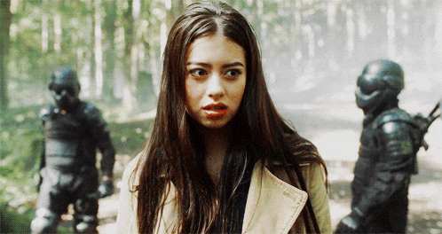 a woman in a trench coat is standing in the woods